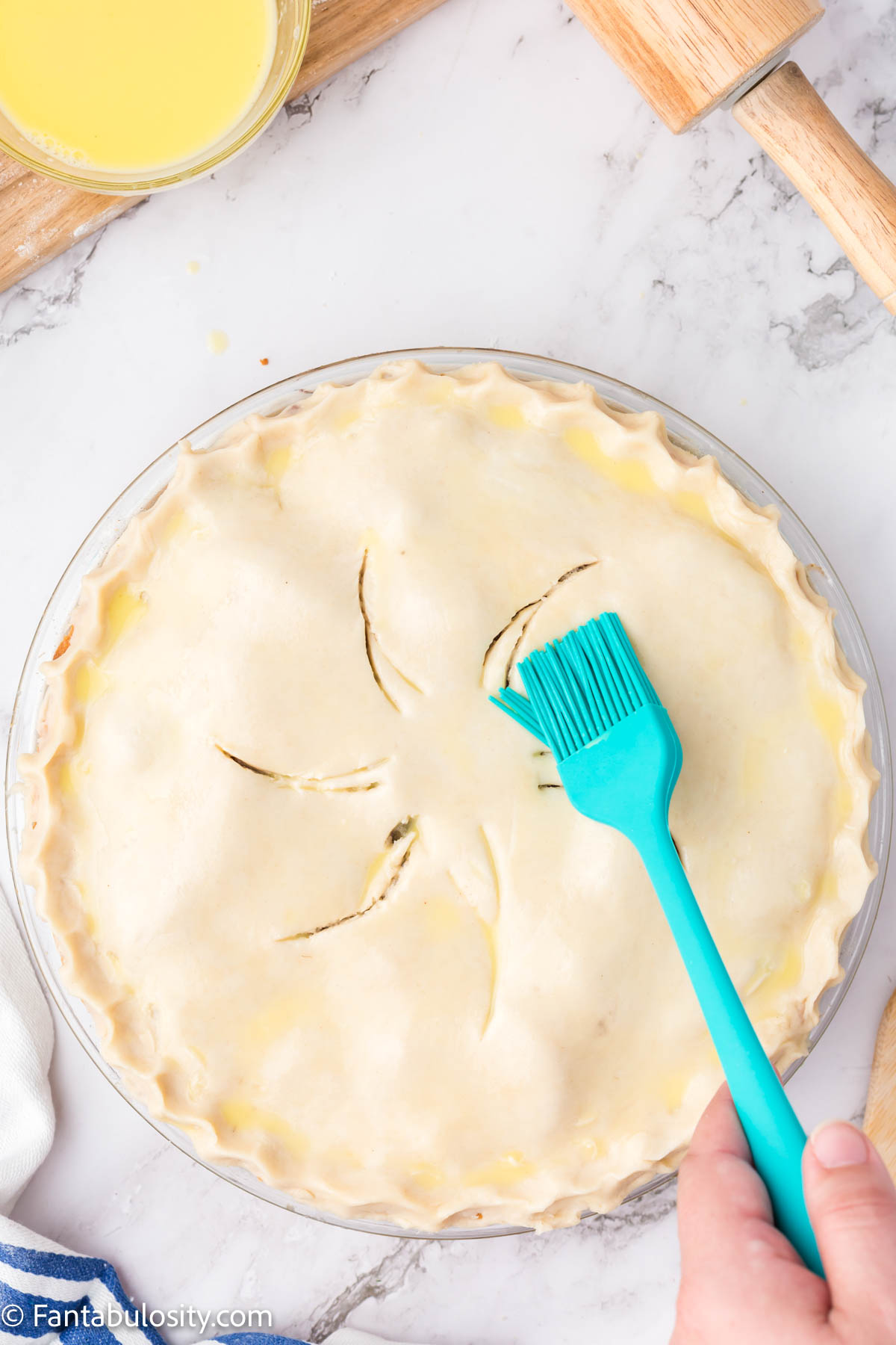 A pastry brush brushing an unbaked pie.