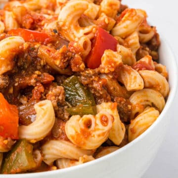 Close up photo of a bowl brimming with noodles, vegetables and ground beef in a rich red tomato based sauce