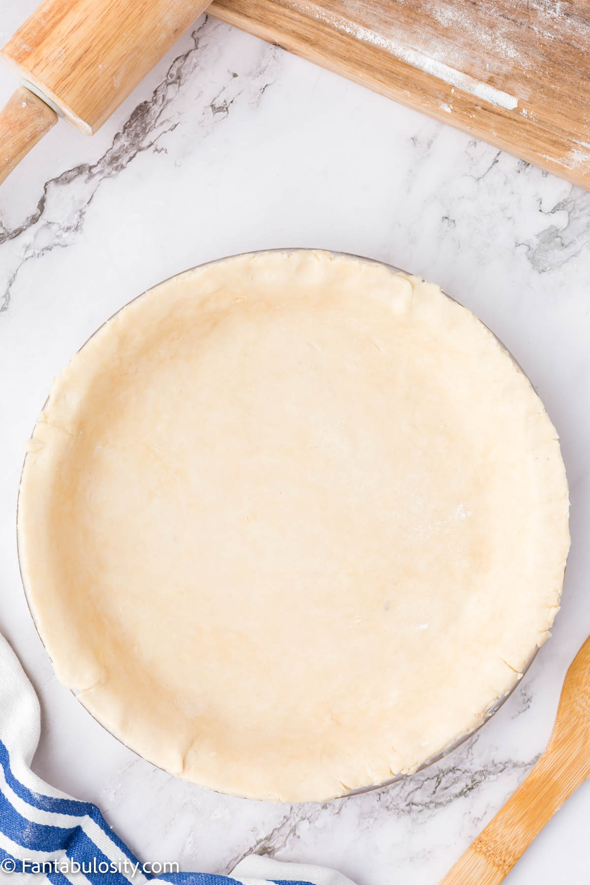 A neatly trimmed pie crust pressed into a pie plate. The edges are trimmed.
