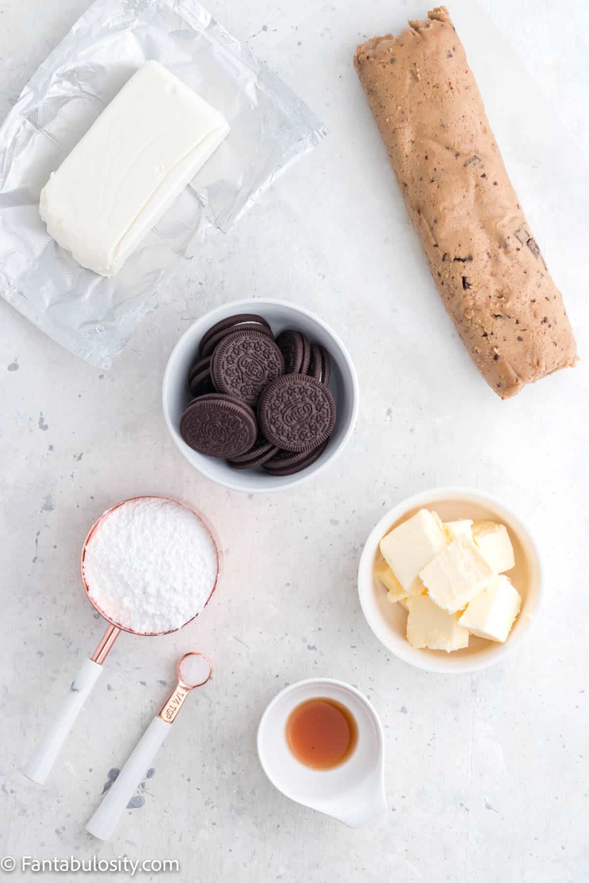 The ingredients used to make an Oreo pizza are laid out on a white marble background