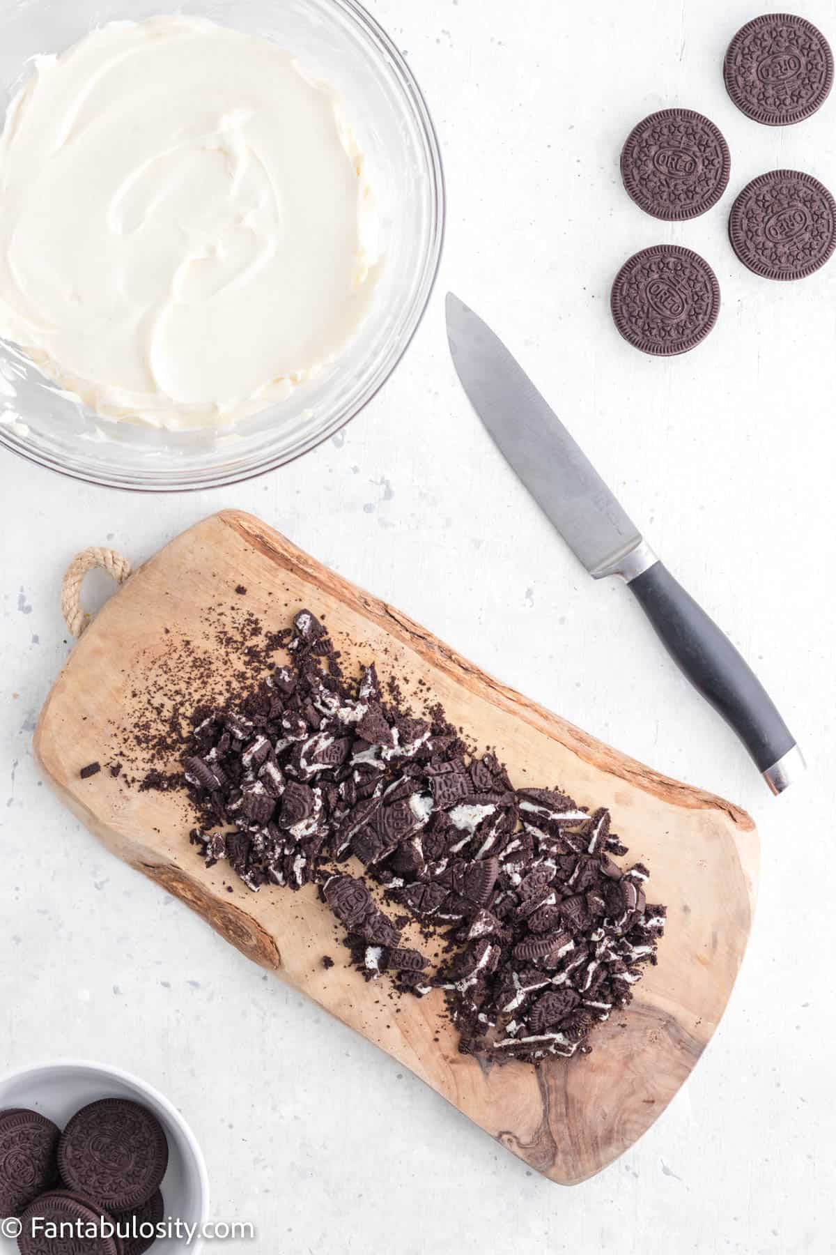 Oreo cookies have been chopped into small pieces on a wooden board