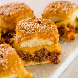 Sloppy joe sliders with melted cheese on white marble cutting board