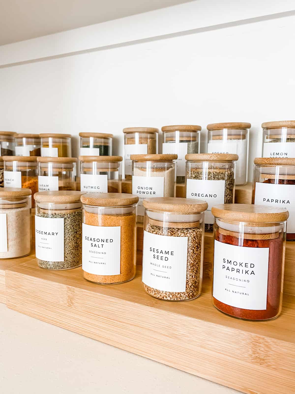 Spices in small glass jars with labels on wooden riser