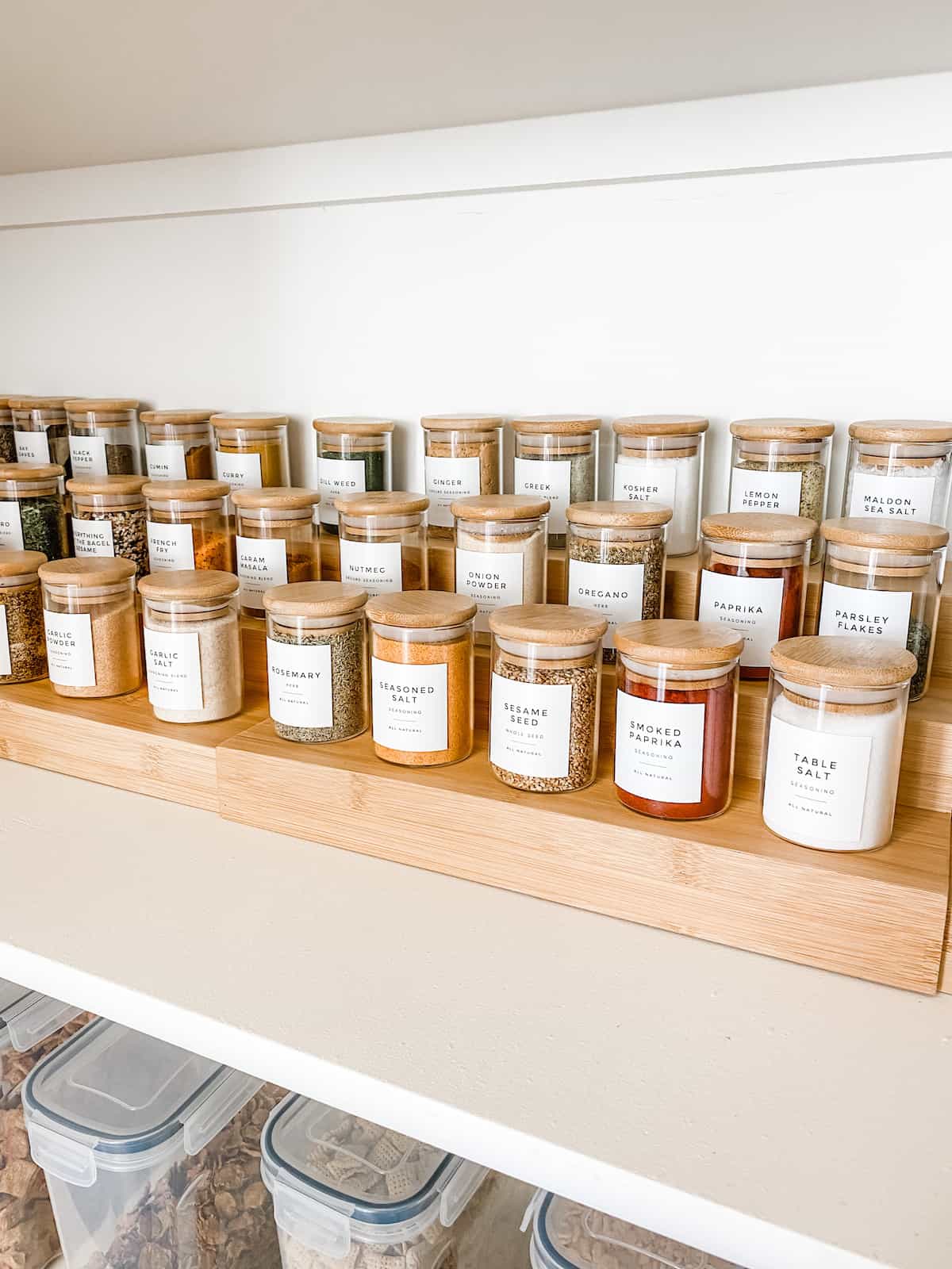 Rows of spices in glass jars on pantry shelf