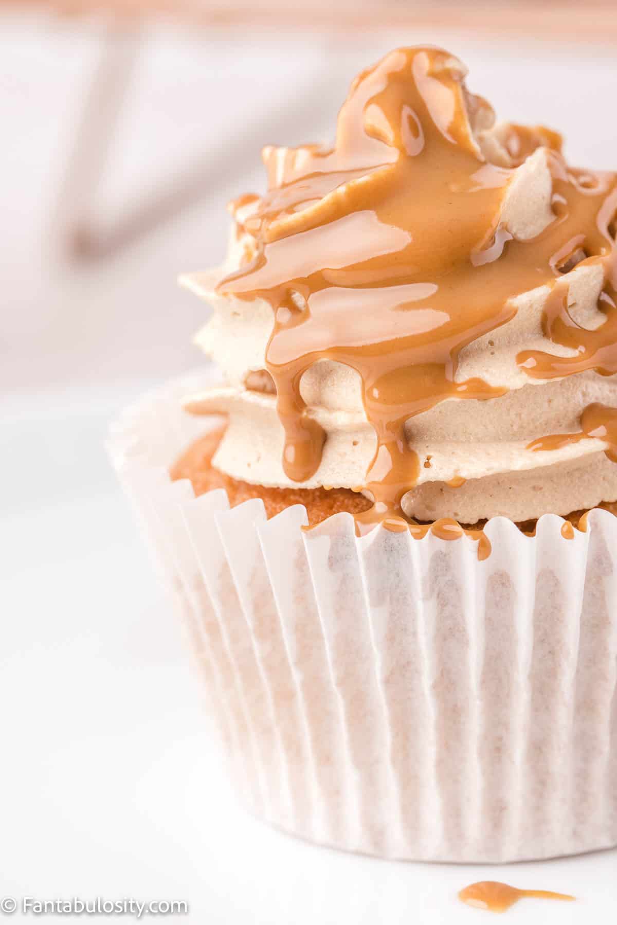 A close up photo of a buttercream frosted cupcake that has been drizzled with melted cookie butter