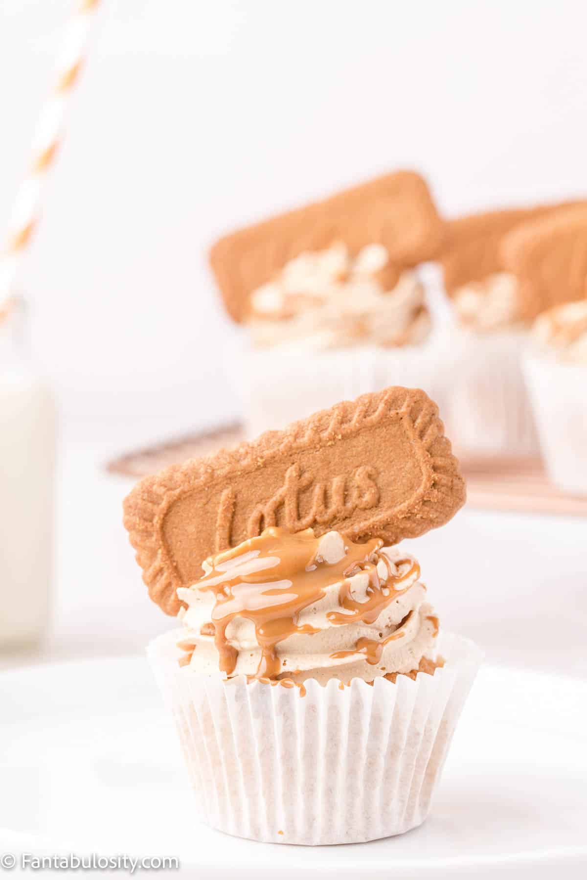 A frosted cupcake has been drizzled with melted cookie butter and topped with a Biscoff cookie