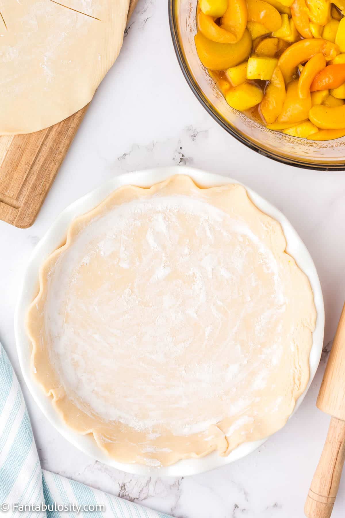 A pie plate with a floured pie crust pressed into it. 