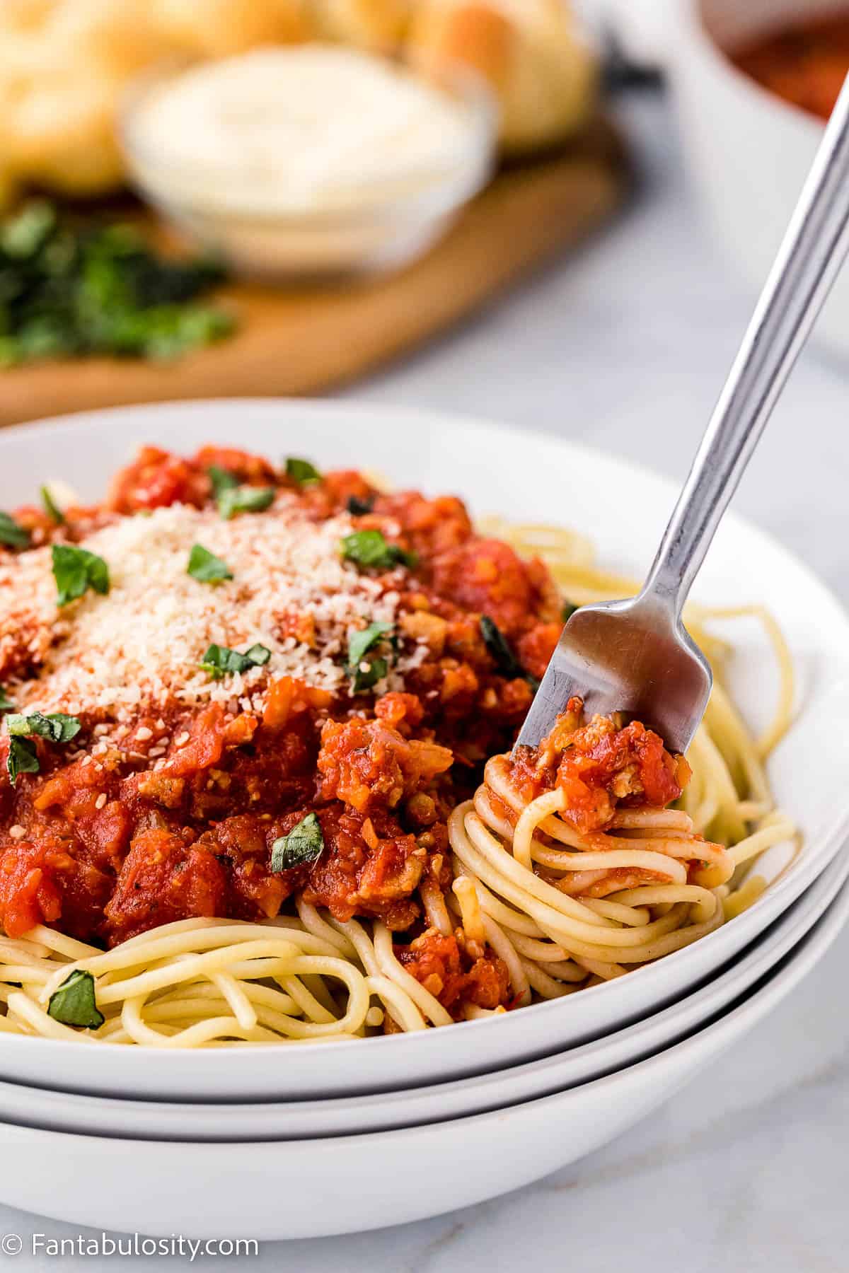 Chicken bolognese sauce on top of spaghetti noodles, with fork taking a bite.