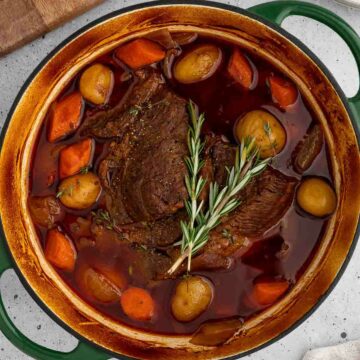 Dutch oven pot roast, with potatoes, carrots and rosemary on top.