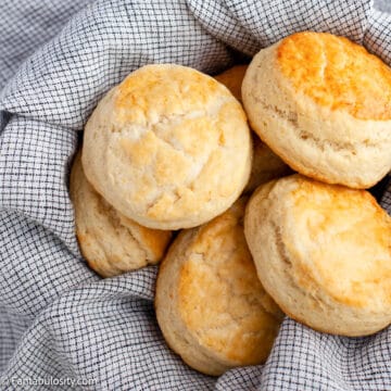 A basket of homemade biscuits lined with a tea towel.