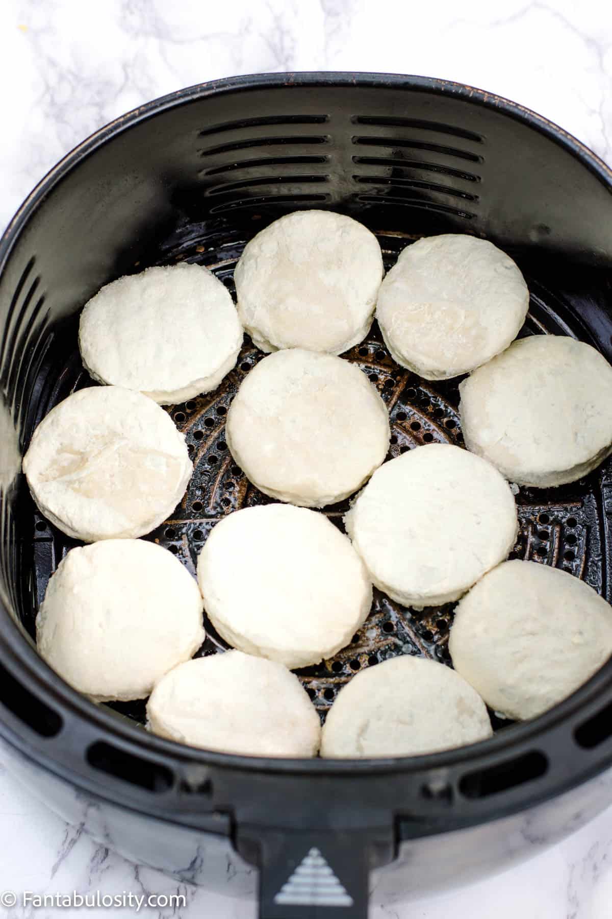 Frozen biscuits in air fryer basket, in a single layer.