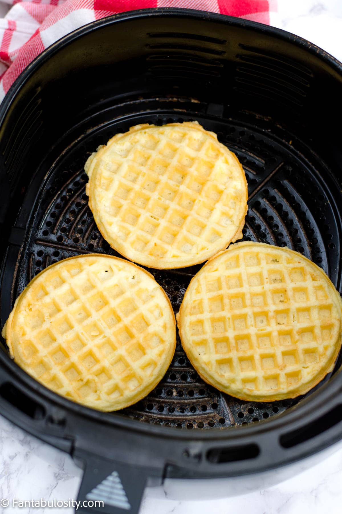 Cooked frozen waffles in the air fryer basket.