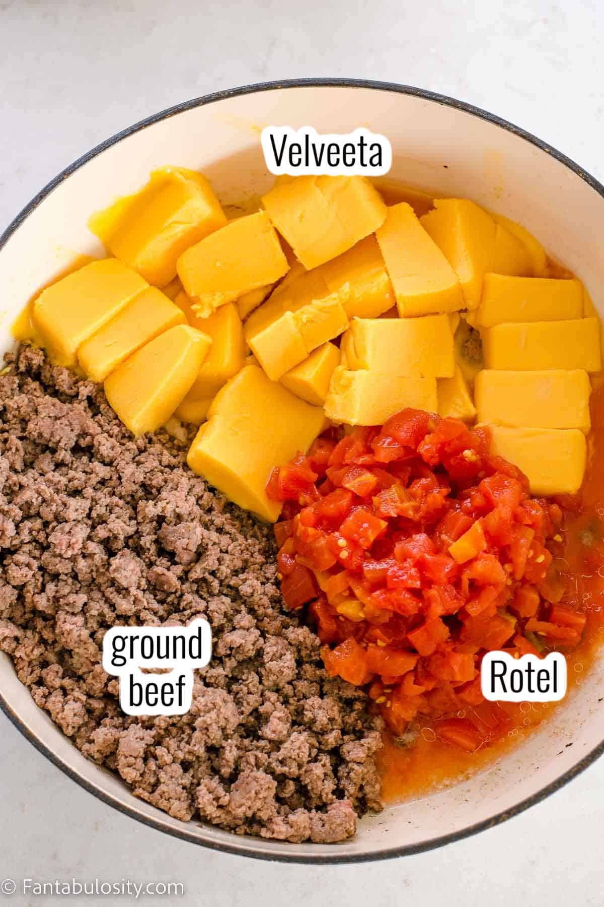 Ingredients in pan for Rotel dip. Velveeta, hamburger, Rotel.
