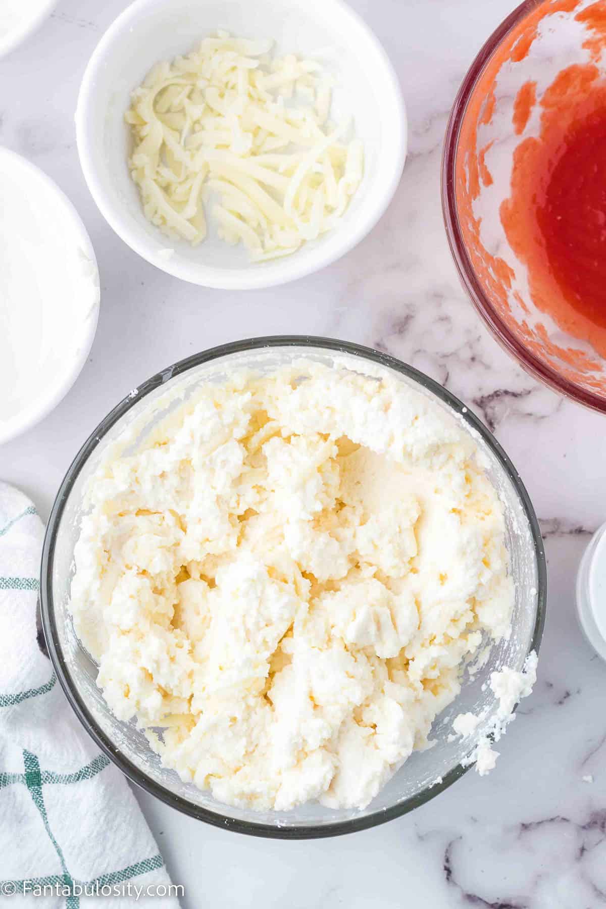 Mixed ricotta and cheeses in clear glass bowl.