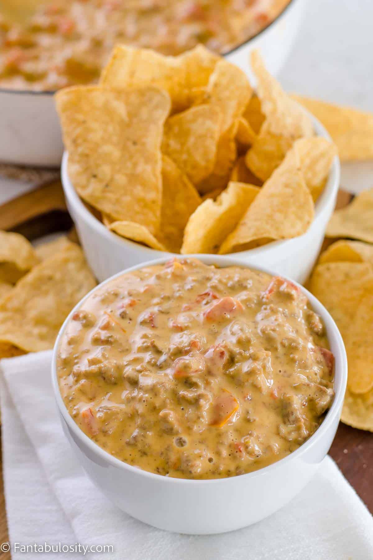 Rotel dip in a white bowl, next to a bowl of tortilla chips.