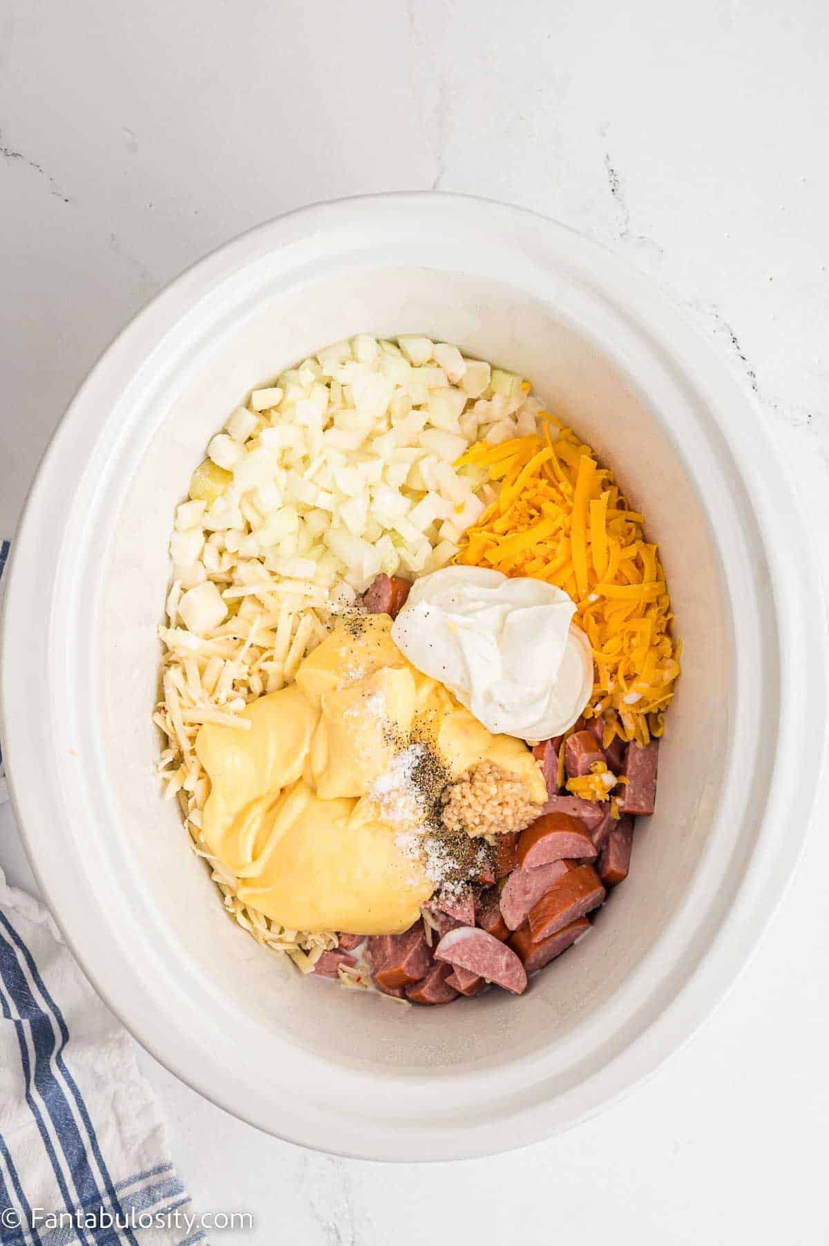 Soup added to slow cooker with potatoes and cheese.