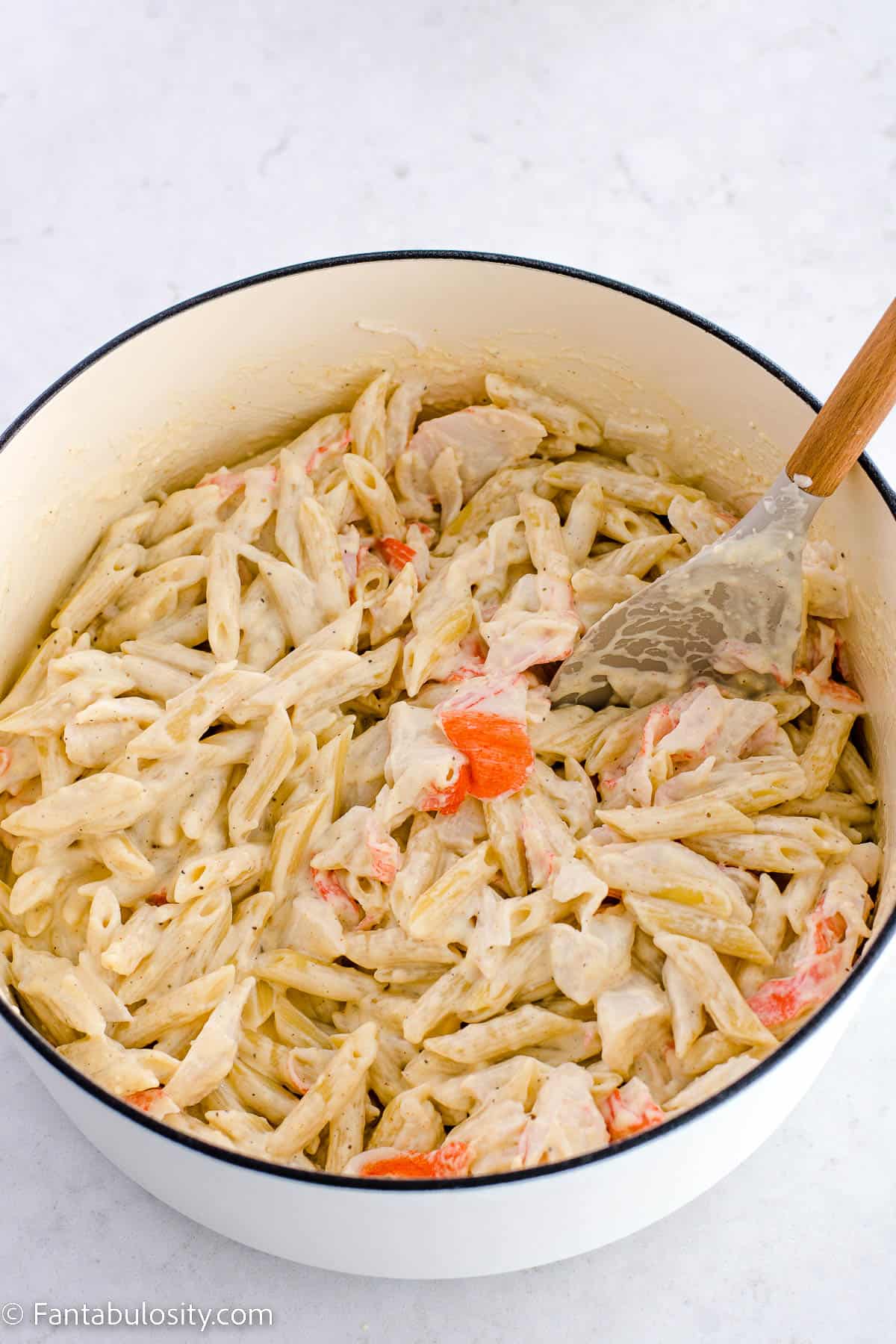 Crab mixed in to alfredo pasta in stock pot.