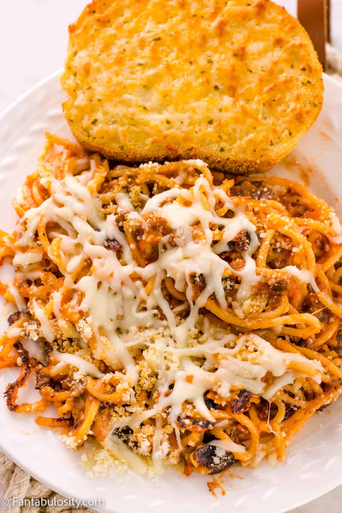 Fried spaghetti on a white plate with a side of Texas toast.