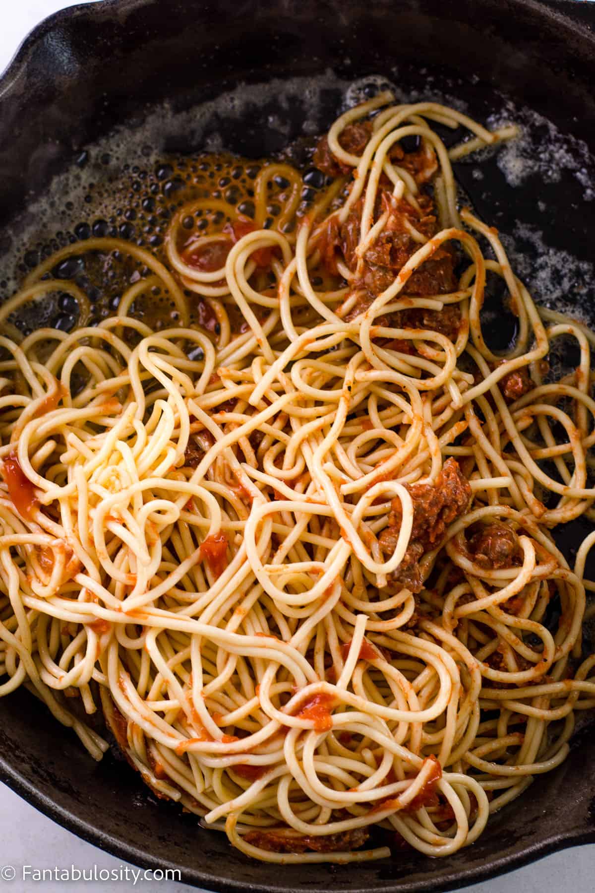 Leftover spaghetti in cast iron pan on top of melted butter.