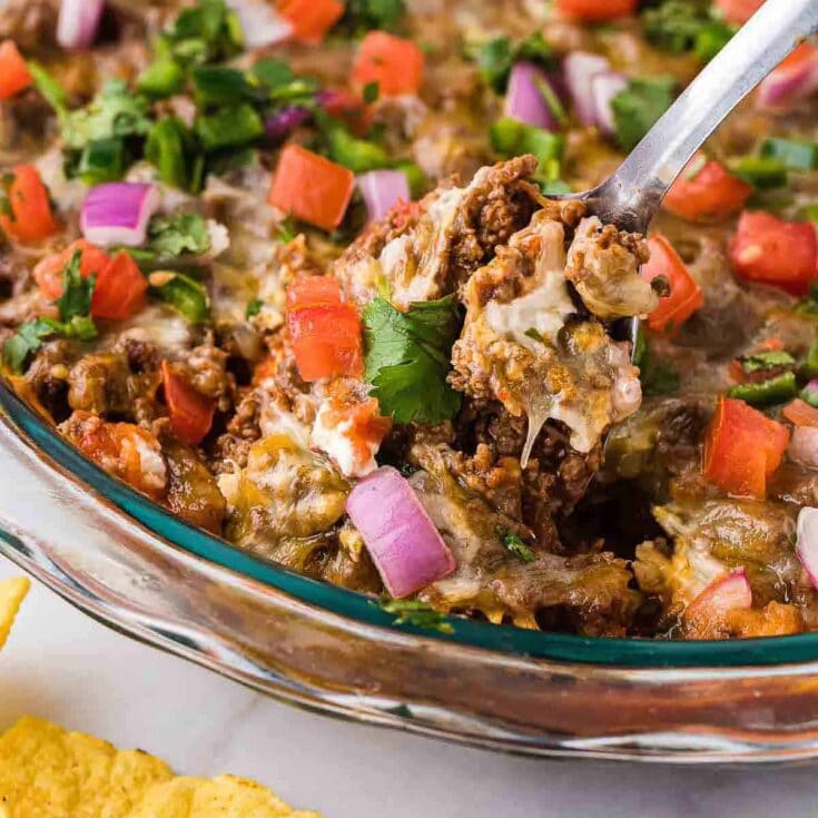 Spoonful of hot taco dip in dish.