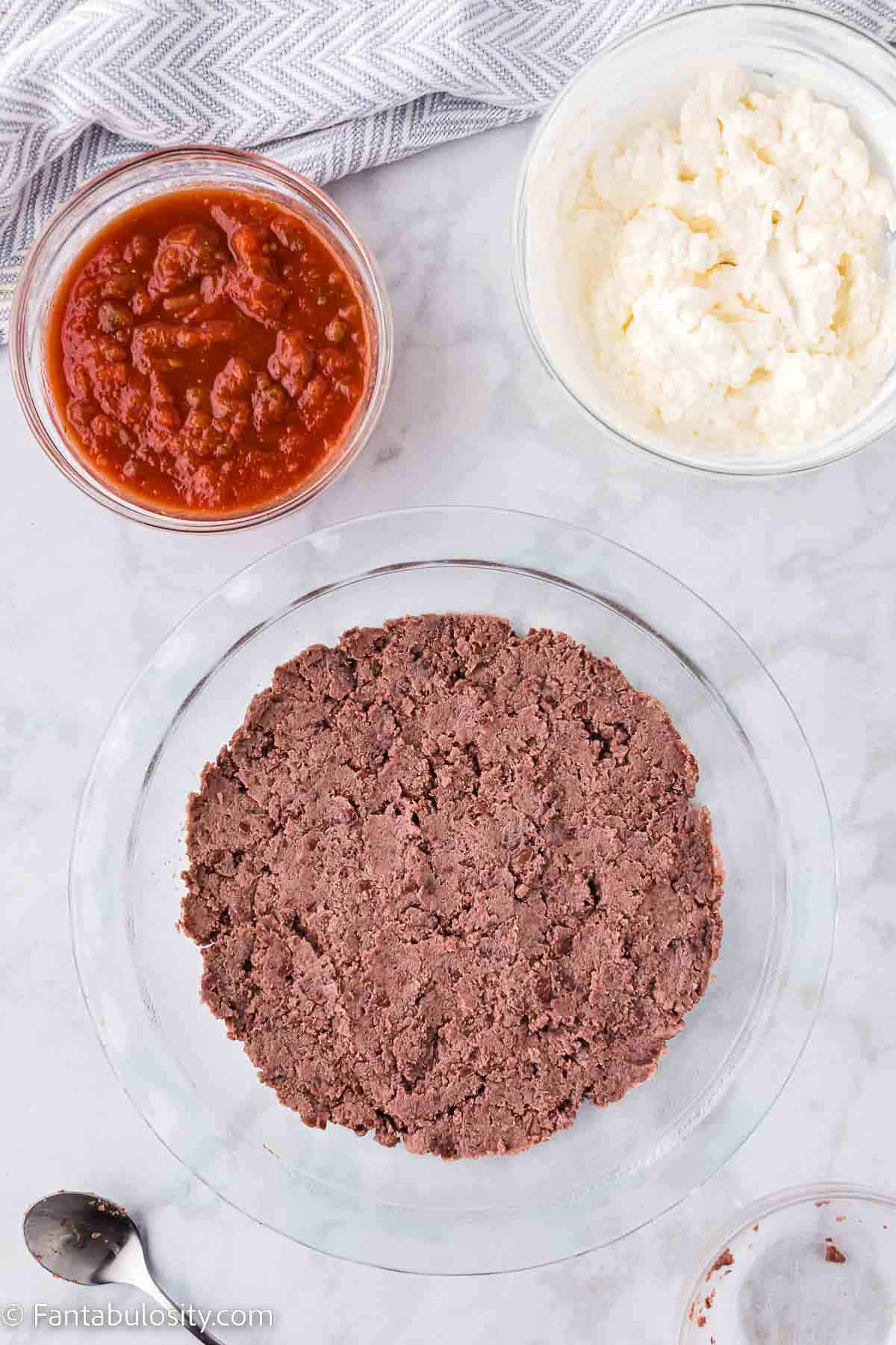 Refried beans layer in baking dish.