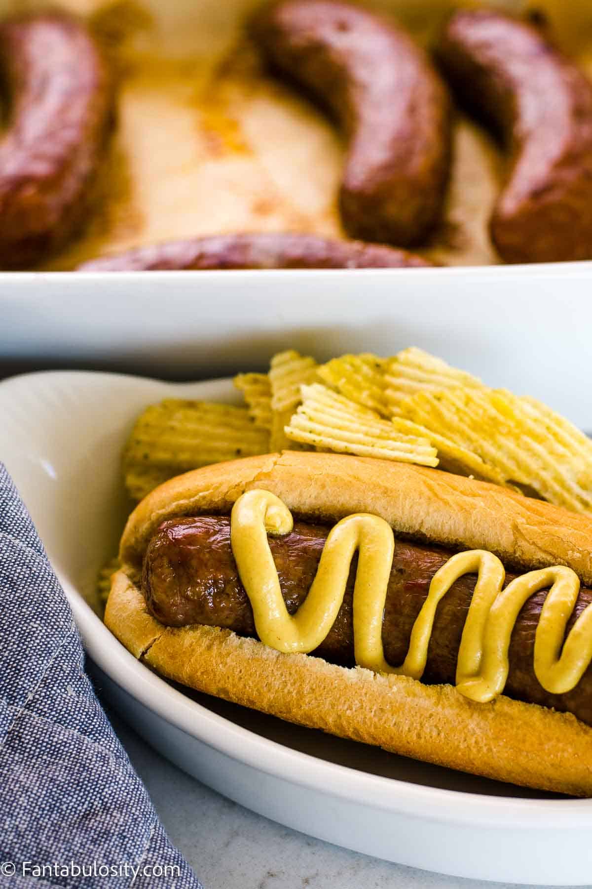 Close up of cooked sausage in hot dog bun with mustard on top.