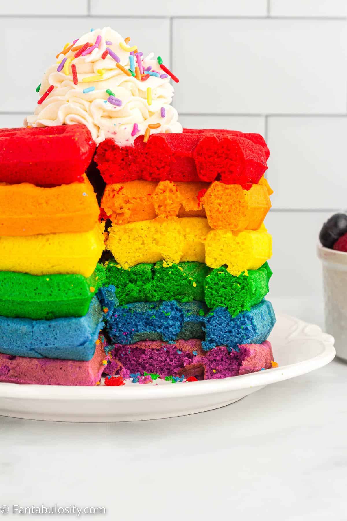 Rainbow waffles on white plate, with section cut out.