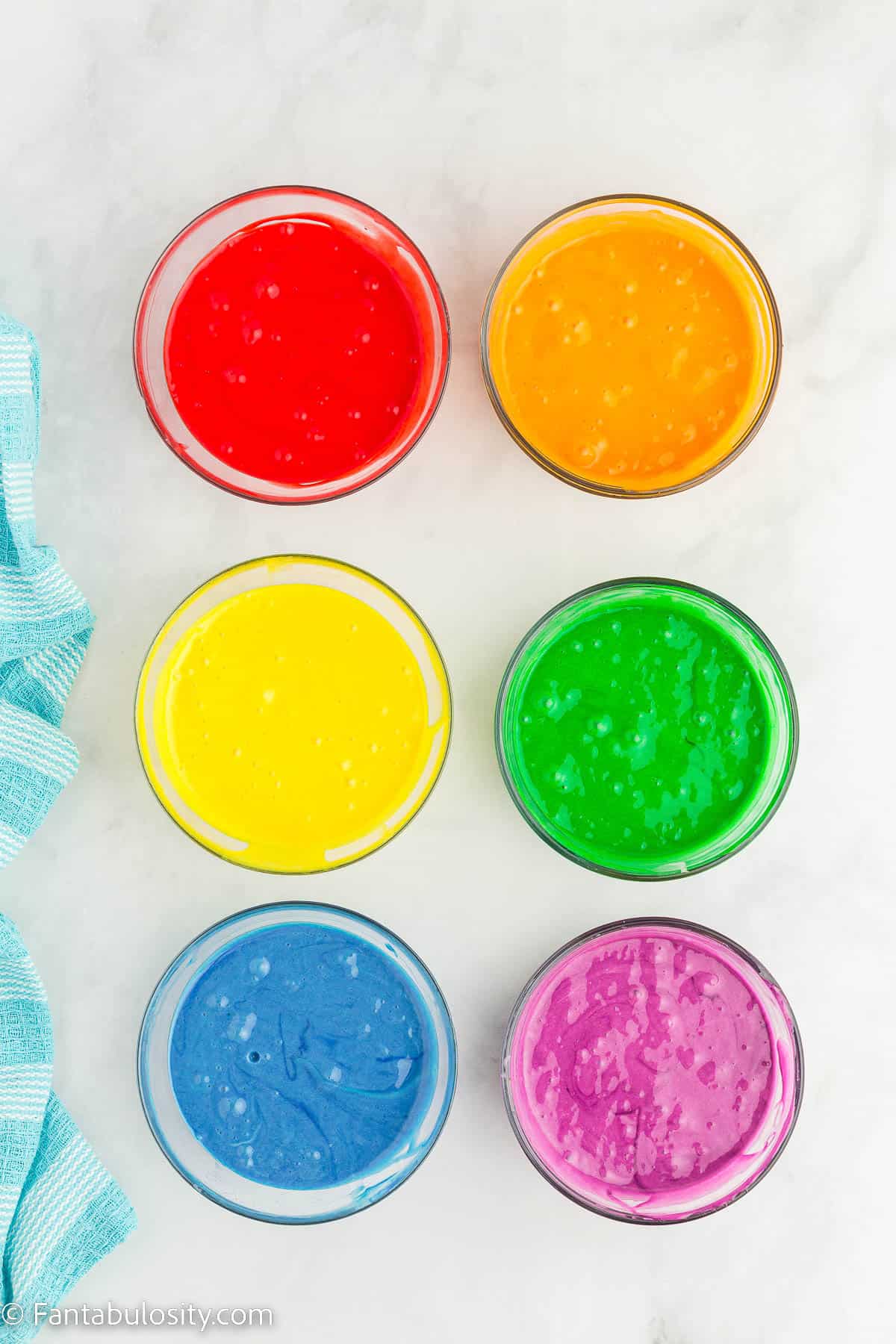 Food coloring added to waffle batter, in small clear glass bowls.
