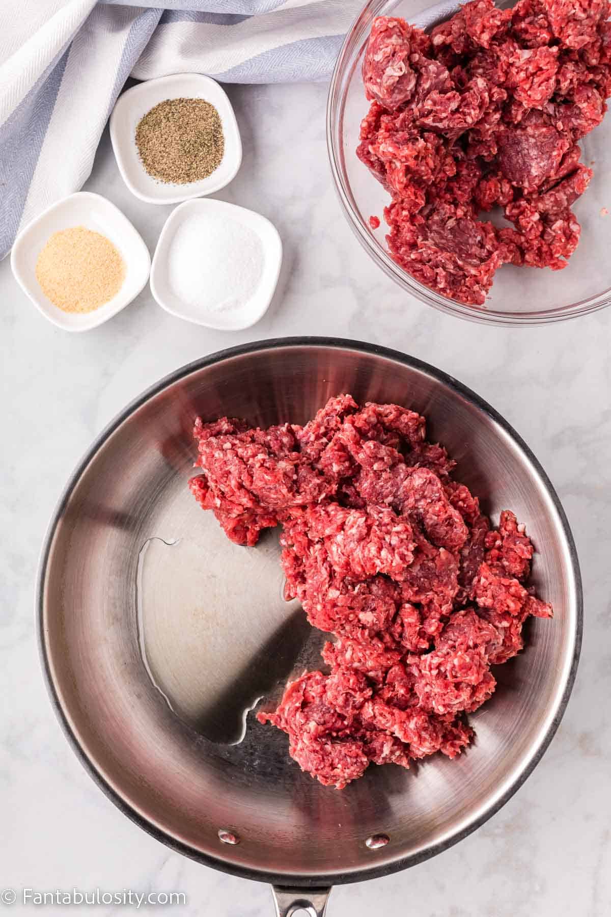 Oil and ground beef in frying pan.