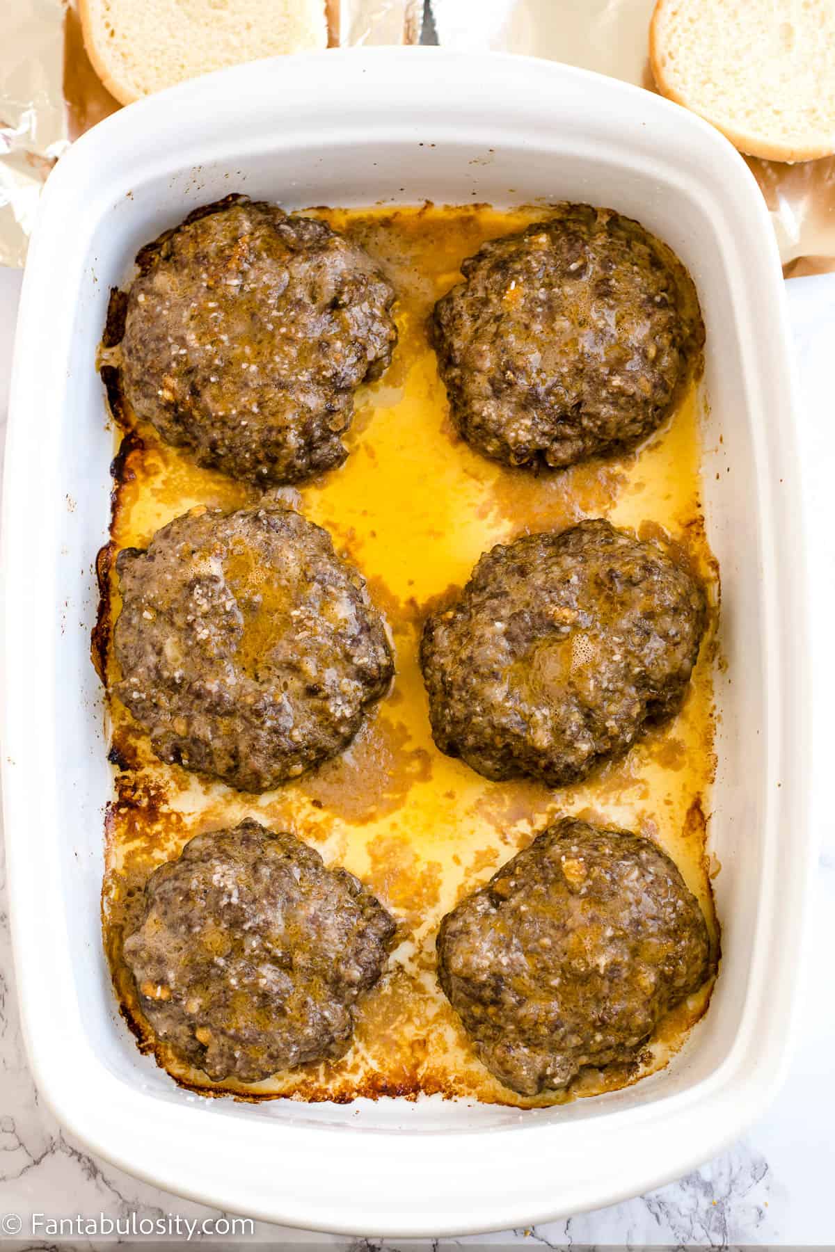 Baked venison burger patties in white baking dish.