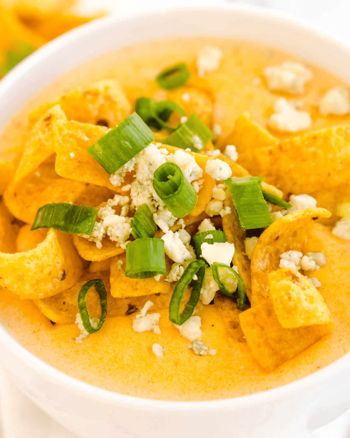 Buffalo chicken soup with fritos and green onions in a white bowl