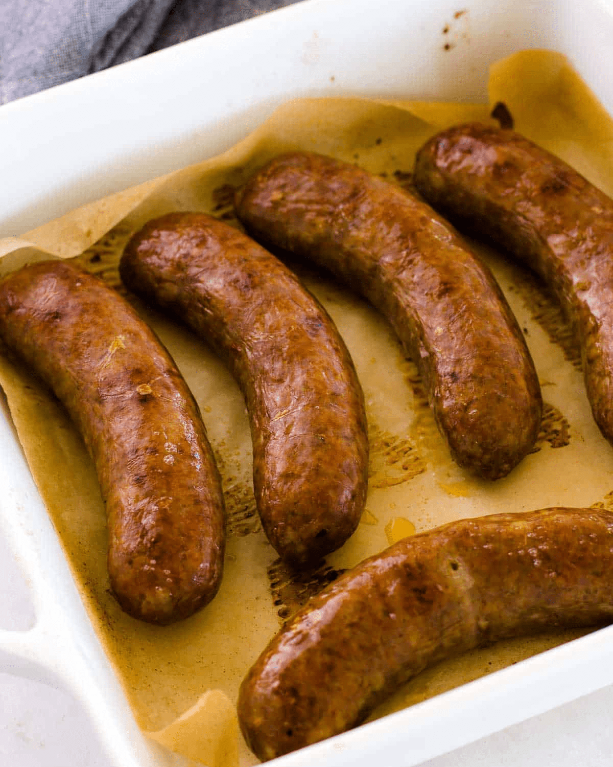 Sausages baked in a white oven dish