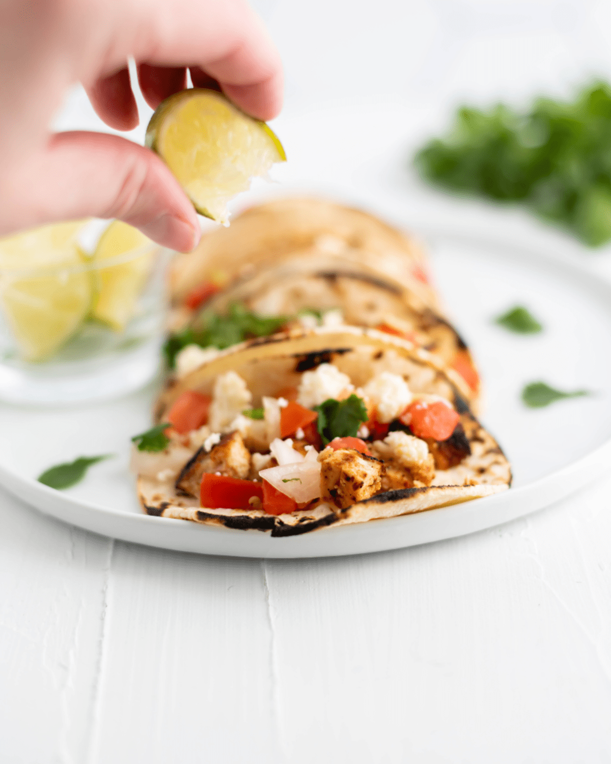 Chicken street tacos with lime juice being squeezed over the tacos