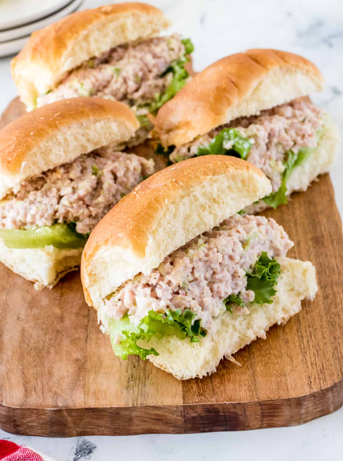 Old fashioned ham salad sandwiches on wooden cutting board.