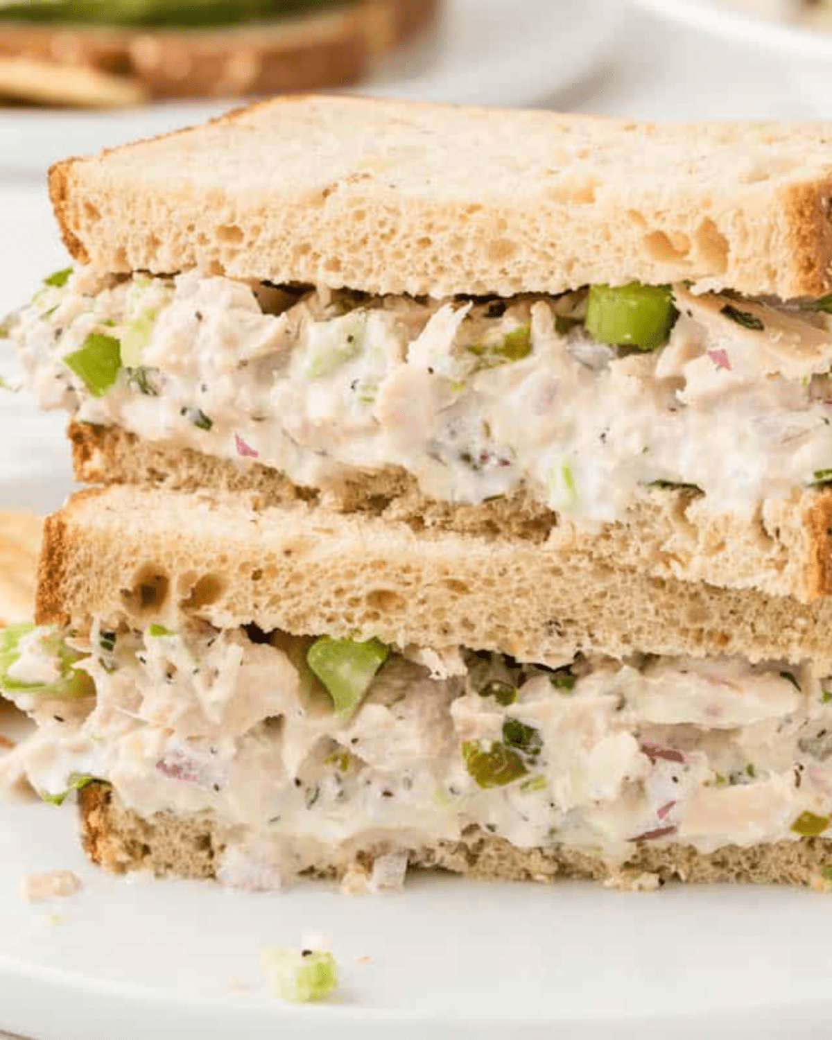 Tuna salad sandwiches stacked up on a white plate