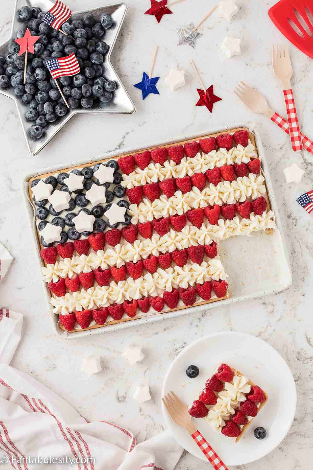 American flag fruit pizza on sugar cookie crust with slice taken out.