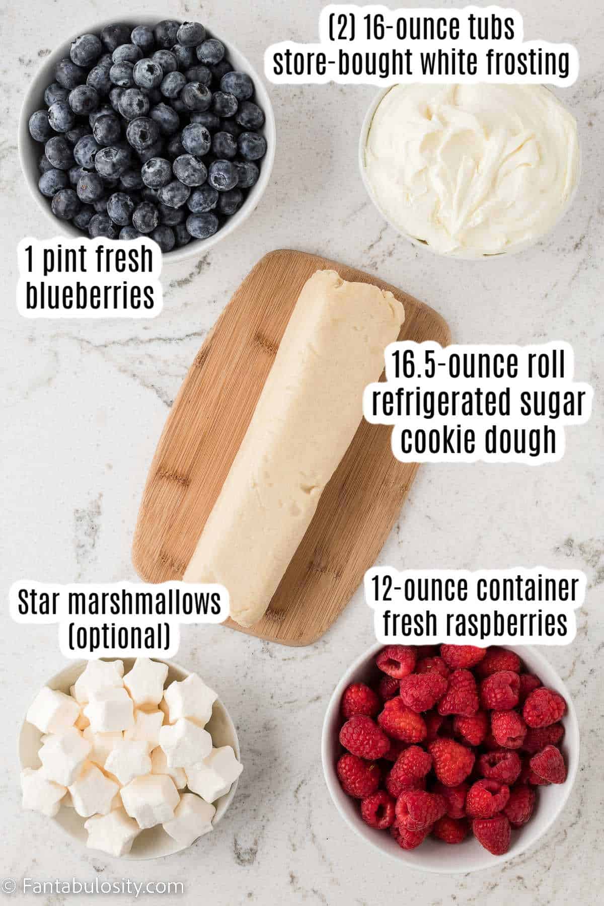 Ingredients for American flag fruit pizza, labeled on white marble.