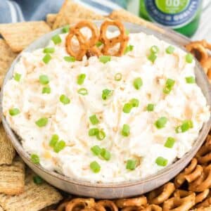 Ranch beer dip in tan bowl, next to pretzels and crackers.