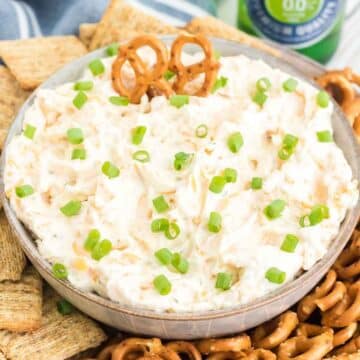 Ranch beer dip in tan bowl, next to pretzels and crackers.
