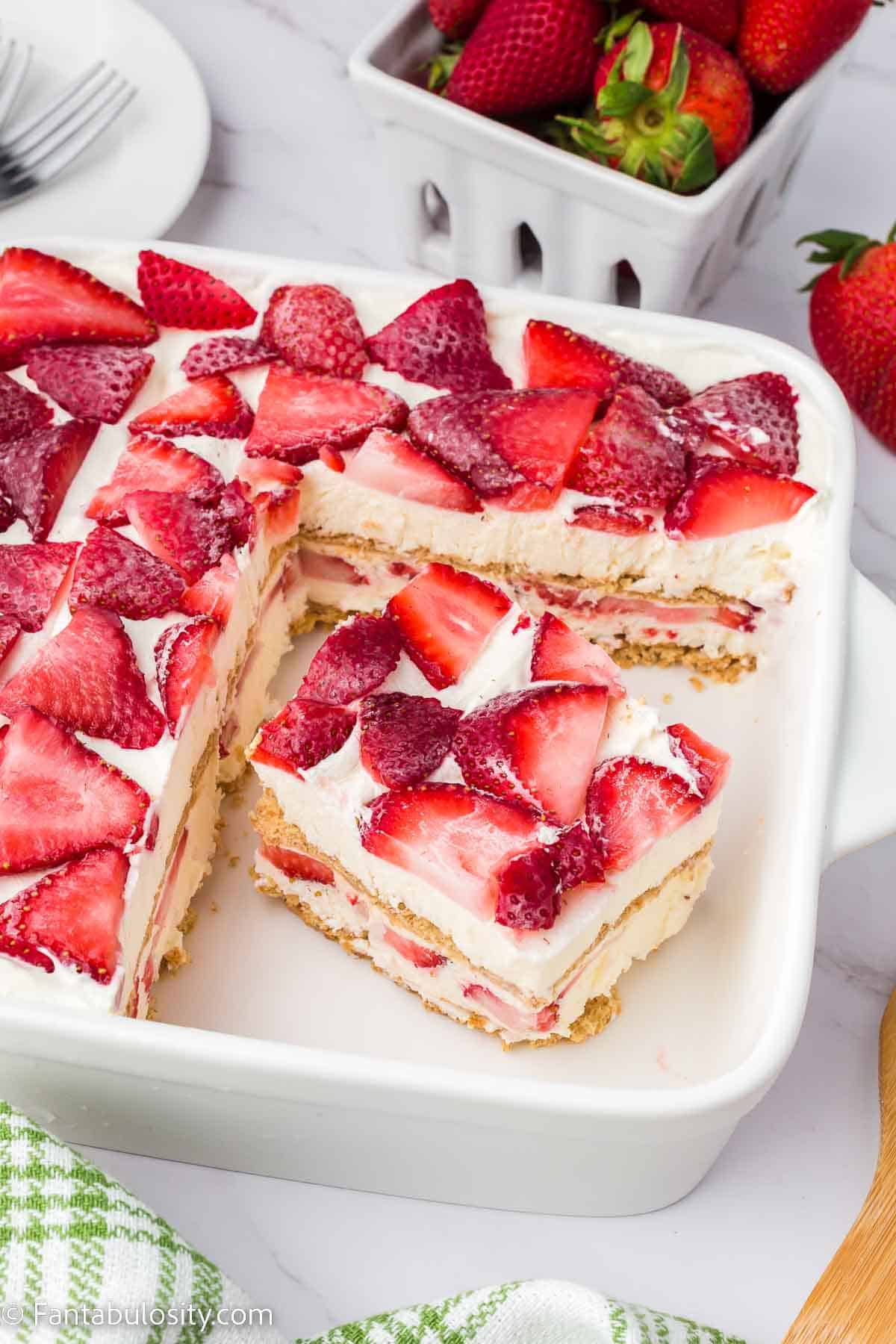 Slice of strawberry cream cheese icebox cake in baking pan.