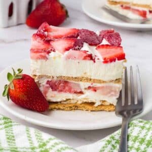 Slice of strawberry cream cheese icebox cake on white plate, next to fork.