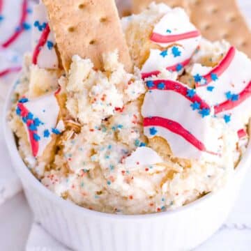 Red white and blue dip in small white bowl, with graham cracker dipped in.