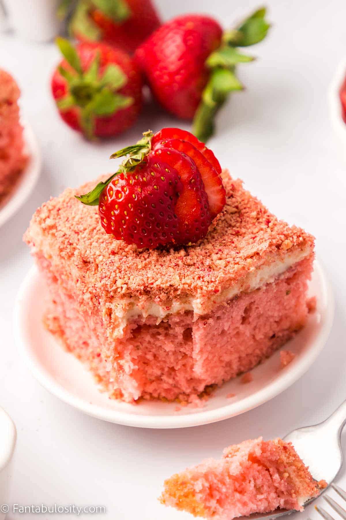 Slice of cake on white plate with bite taken out with fork.