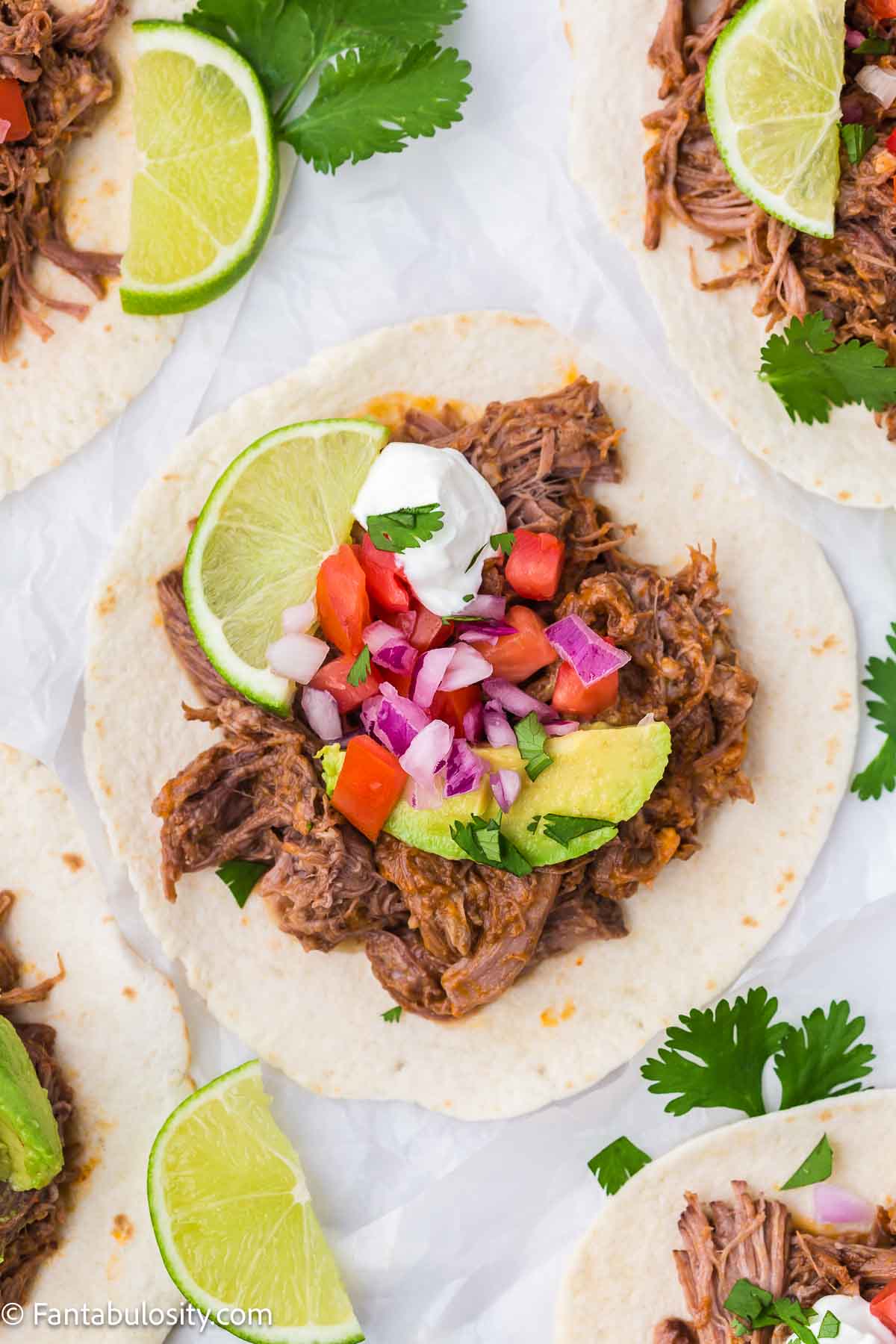 Slow cooker beef taco on tortilla with toppings.