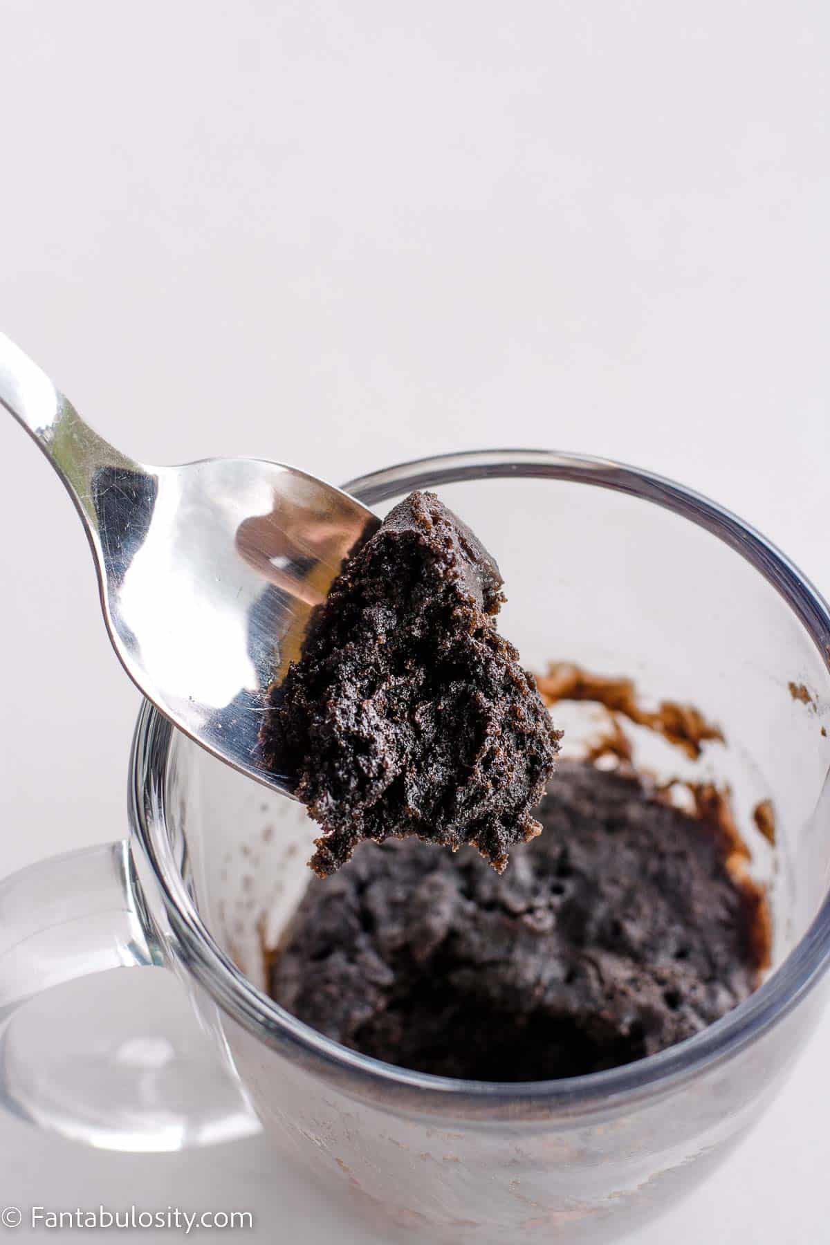 Cooked Oreo mug cake with spoon lifting out a bite.