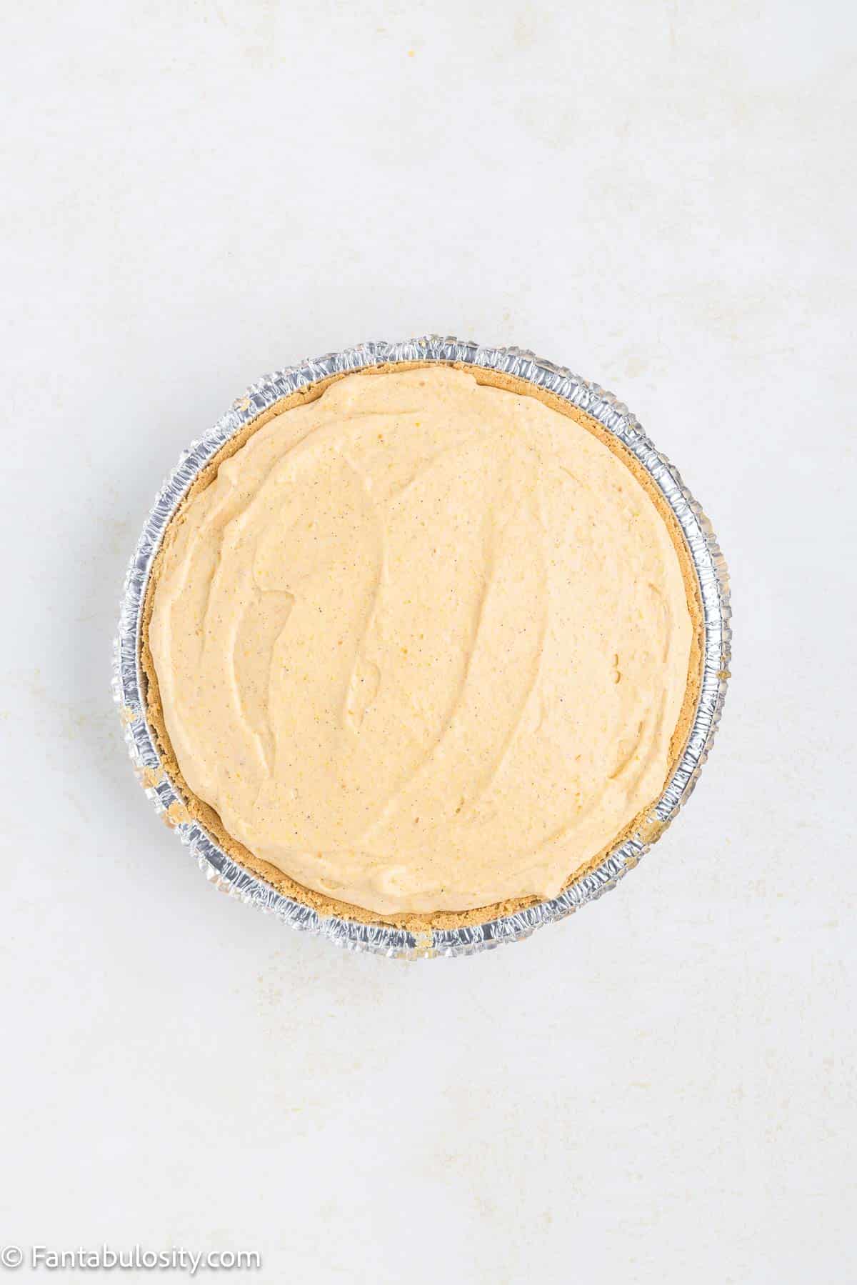 No bake pumpkin pie in graham cracker crust, sitting on kitchen counter.