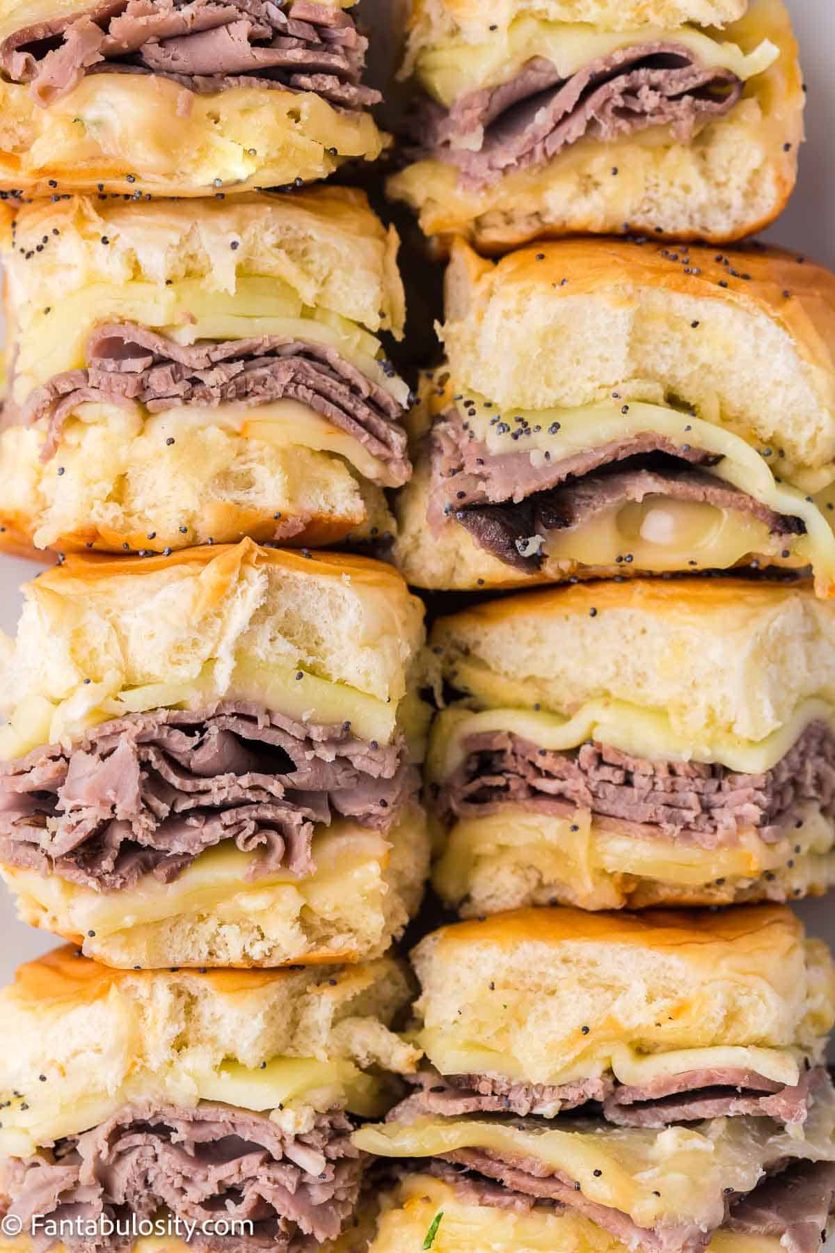 Close-up of roast beef sliders, laying on their side, in baking dish.