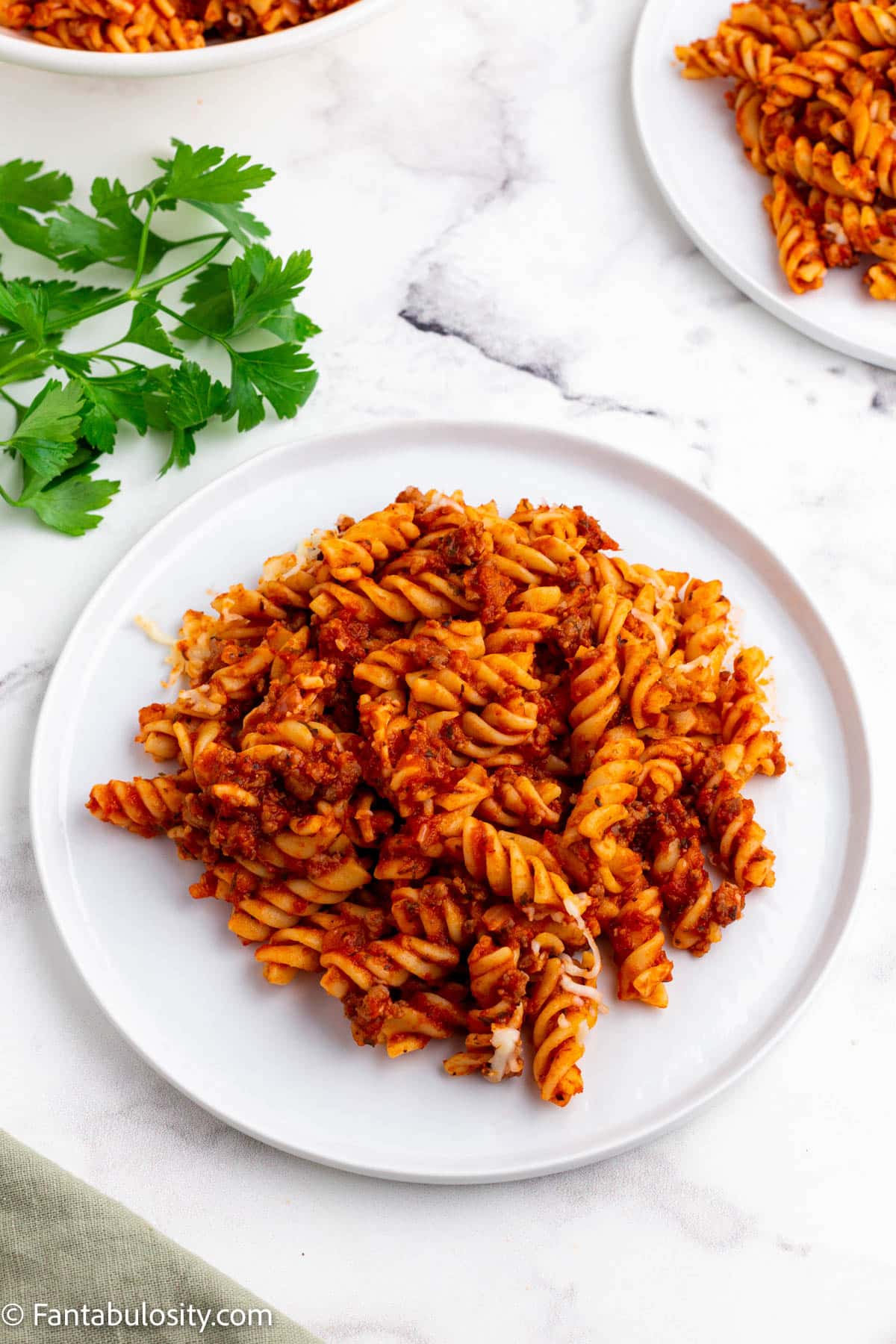 Serving of sausage pasta bake on white plate.