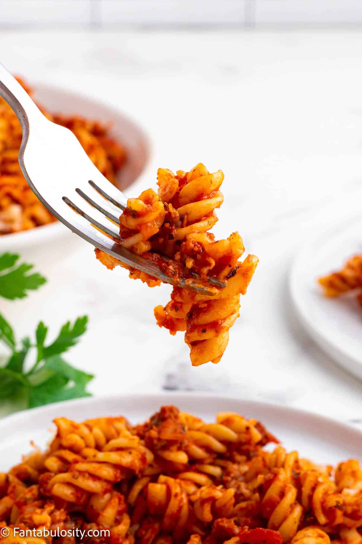 Fork holding a bite of sausage pasta bake.