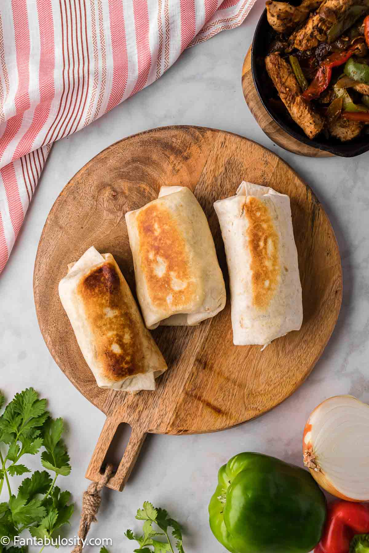 Cooked fajita wraps on wooden cutting board.